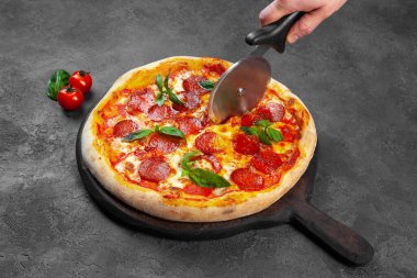 Kadın eli, fesleğenli pepperoni pizza dilimi.