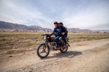 Moğolistan Ulgii 2019-05-04 Moğol erkekleri köyün arkasındaki bozkırda motosiklet sürerler ve selamlarını gönderirler. Otantik yerel Asya taşımacılığını kabul et