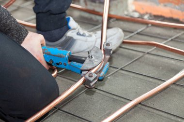 Erkek elleri borularla bakır boruları büker.