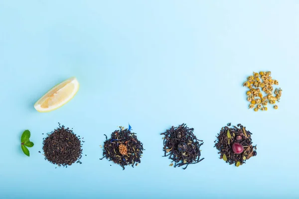 Heaps of different black and herbal tea on blue background — Stock Photo, Image