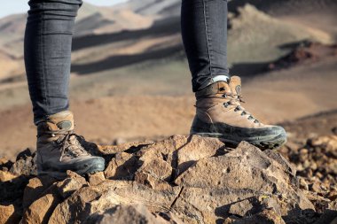 Gün batımında dağda yürüyen yürüyüş botları içinde bir turist.