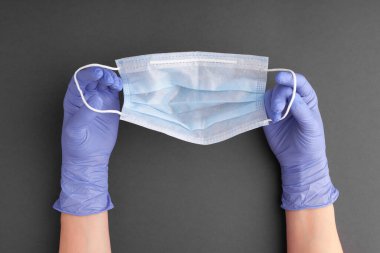 Lastik eldivenli kadın eli tek kullanımlık tek kullanımlık yüz maskesi tutuyor.