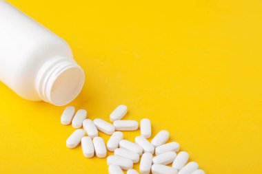 Çeşitli ilaç vitaminleri, haplar, beyaz şişeden yayılmış haplar.