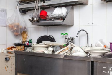 Kirli bulaşık, çanak çömlek, sofra takımı dolu bir metal lavabo.