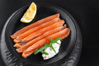 Taze tuzlanmış somon, limon ve peynirli tabakta.