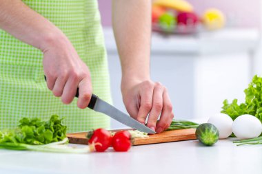 Önlüklü bir aşçı kadın evdeki mutfakta taze sağlıklı sebze salatası için çevre dostu ürünler doğruyor. Diyet ve temiz yemek. Sebze yemekleri için hazırlık