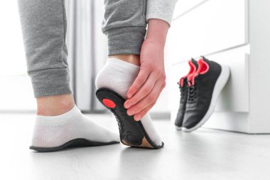 Ortopedik tabana uyan sporcu kadın. Düz taban ve ayak ortopedik hastalıklarının tedavisi ve önlenmesi. Ayak bakımı, ayak rahatlığı. Sağlık hizmetleri. Spor ayakkabıları giyiyorlar.