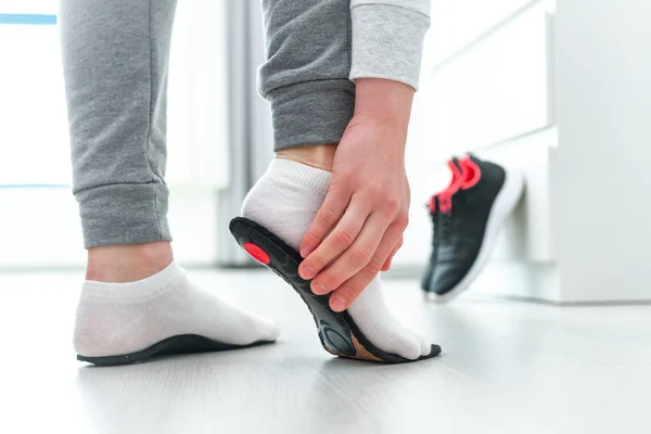 Ortopedik tabana uyan sporcu kadın. Düz taban ve ayak ortopedik hastalıklarının tedavisi ve önlenmesi. Ayak bakımı, ayak rahatlığı. Sağlık hizmetleri. Spor ayakkabıları giyiyorlar.