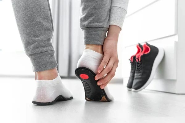 Ortopedik tabana uyan sporcu kadın. Düz taban ve ayak ortopedik hastalıklarının tedavisi ve önlenmesi. Ayak bakımı, ayak rahatlığı. Sağlık hizmetleri. Spor ayakkabıları giyiyorlar.