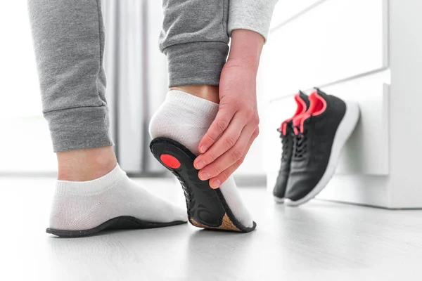 Ortopedik tabana uyan sporcu kadın. Düz taban ve ayak ortopedik hastalıklarının tedavisi ve önlenmesi. Ayak bakımı, ayak rahatlığı. Sağlık hizmetleri. Spor ayakkabıları giyiyorlar.