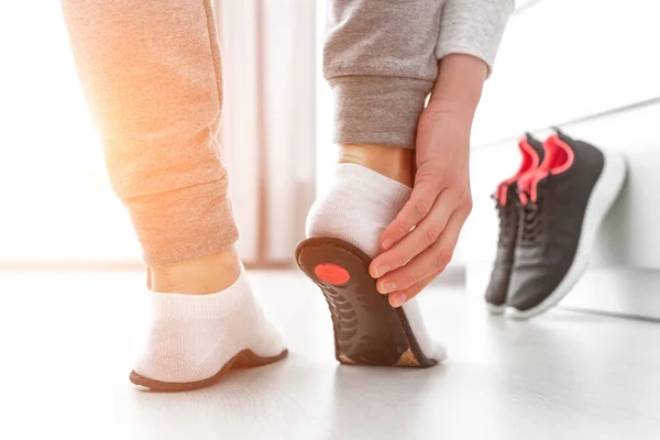 Ortopedik tabana uyan sporcu kadın. Düz taban ve ayak ortopedik hastalıklarının tedavisi ve önlenmesi. Ayak bakımı, ayak rahatlığı. Sağlık hizmetleri. Spor ayakkabıları giyiyorlar.