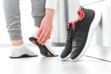 Kadın ortopedik taban giyiyor. Düz taban ve ayak hastalıklarının tedavisi ve önlenmesi. Ayak bakımı, ayak rahatlığı. Sağlık hizmetleri. Spor ayakkabıları giyiyorlar.