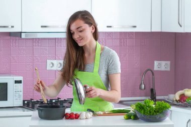 Önlüklü bir kadın evde öğle yemeği için olgun sebzelerden yemek hazırlıyor. Temiz yemek ve düzgün beslenme. Sağlıklı yaşam tarzı, diyet 
