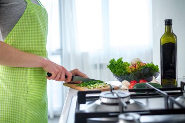 Önlüklü bir kadın sebze tabağı ve evde taze salata için sebze doğradı. Akşam yemeği için yemek hazırlığı. Temiz sağlıklı yiyecekler ve düzgün beslenme. 