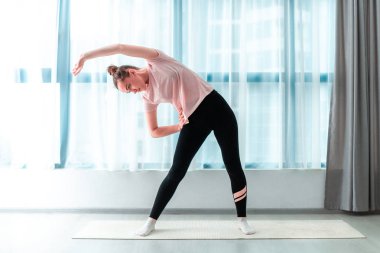 Genç bir kadın evde yoga minderinin üzerinde kaslarını esnetiyor ve spor yapıyor. Kilo ver ve formda ol. Sağlıklı spor yaşam tarzı 