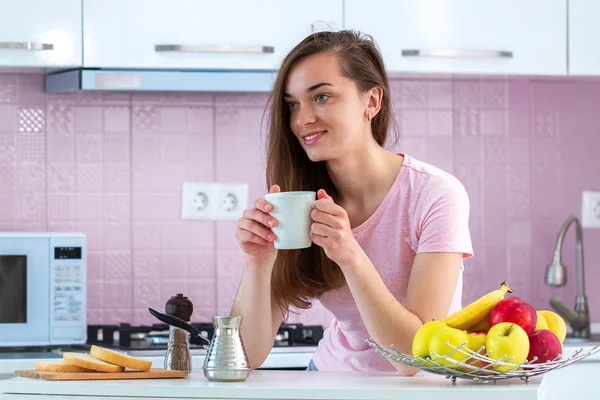 Young, attractive, woman drinks hot, tasty coffee for breakfast in early morning at kitchen at home. Good morning and start new day