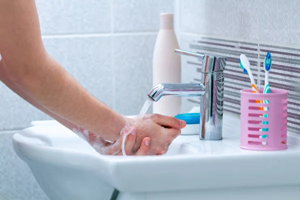 Washing hands under the tap with water in bathroom. Hygiene and hand care