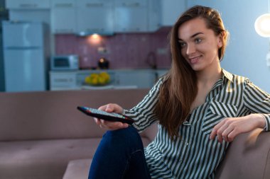 Genç, mutlu, gülümseyen kadın dinleniyor ve evde televizyon izliyor.. 