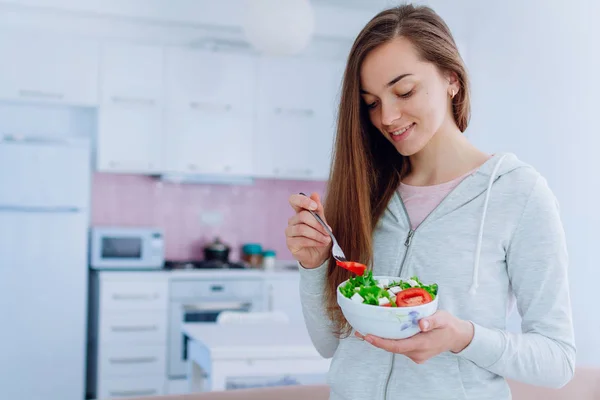 Young happy beautiful vegan woman eating healthy vegetable salad for lunch at home. Diet and fitness eating. Clean and control food