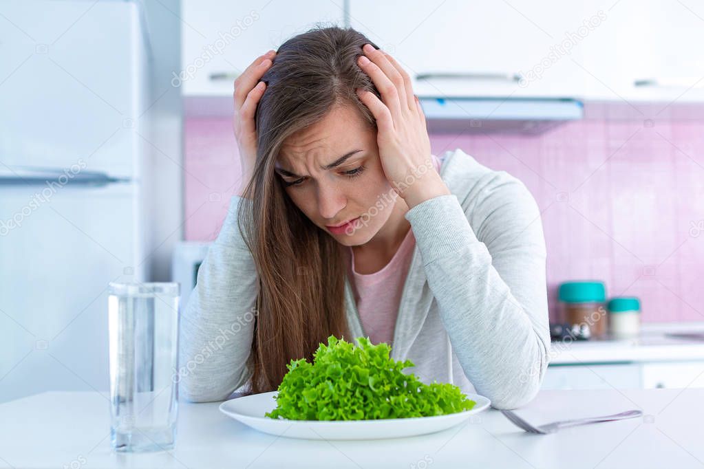 Sad unhappy woman is tired of dieting and not wanting to eat organic, clean healthy diet food