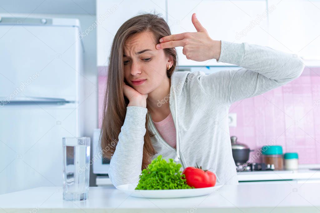 Sad unhappy woman is tired of dieting, exterminate yourself with a diet and forcing yourself to eat organic, clean healthy food