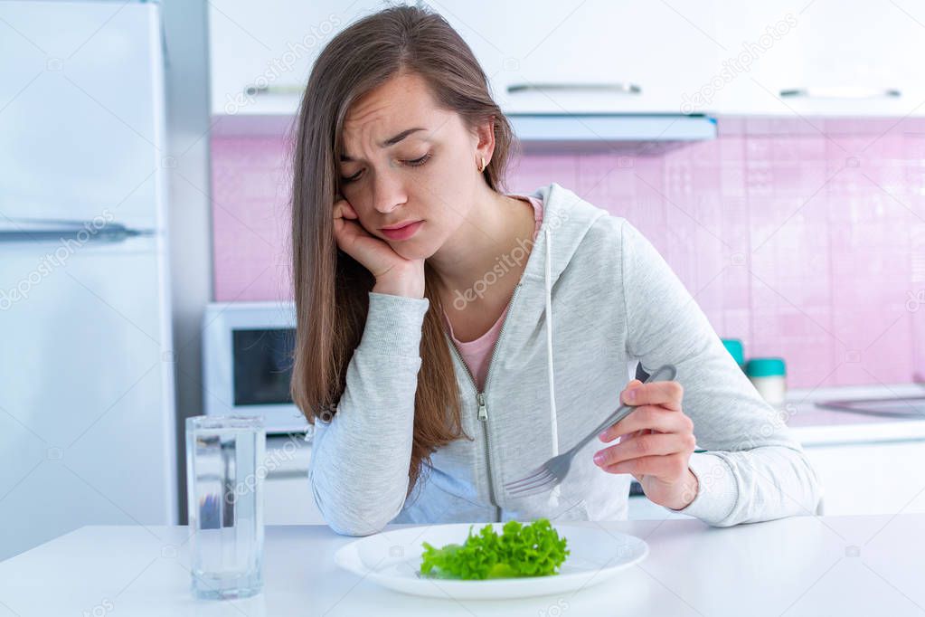 Sad unhappy young woman is tired of dieting and not wanting to eat organic, clean healthy food