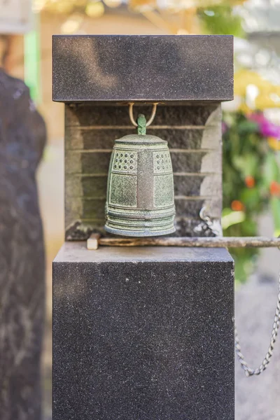 Small bronze bell hanging at the foot of Habataki Kanzeon Bosatsu statue in Tabata Togakuji temple in Tokyo.