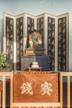 Tokyo, Japonya - 3 Ocak 2019: Shinto tanrısı Ebisu 'nun tahta heykeli, bir ekran, bir kagami mochi pirinç keki ve kazınmış bir bağış kutusu.