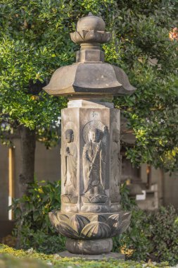 tokyo, japan - january 07 2019: Six Jizo statues on an hexagonal memorial stone stand where is engraved in japanese ideographs Spirit of the realm reality with two vases ornate with coat of arms of eagle feathers in the Tokyo Tennoji.