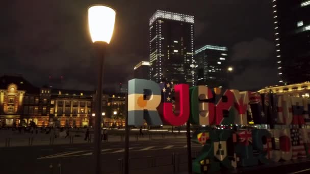 Video van een reusachtig typografisch monument met de inscriptie Rugby World Cup 2019 Japan voor het Tokyo Station 's nachts. — Stockvideo