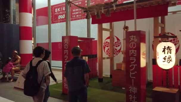 Vidéo d'un monument promotionnel à la gare de Tokyo pour la Coupe du monde de rugby 2019 au Japon avec un sanctuaire japonais dédié au rugby et un sumo tenant une balle de rugby sur un banc . — Video