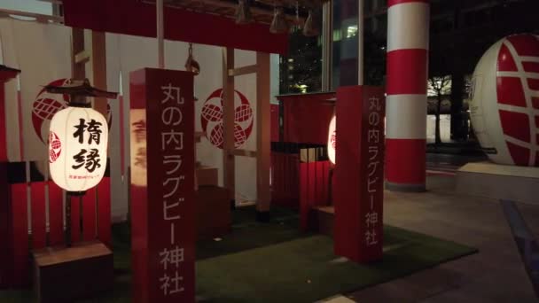 Vídeo de un monumento promocional en la Estación de Tokio para la Copa Mundial de Rugby 2019 en Japón con un santuario japonés dedicado al rugby y un sumo sosteniendo una pelota de rugby en un banco . — Vídeo de stock