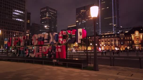 Videó egy hatalmas tipográfia emlékmű, ahol felirat Rugby World Cup 2019 Japán előtt a tokiói állomás éjjel. — Stock videók