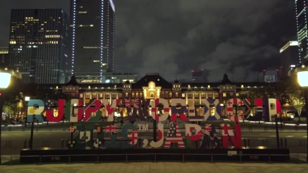 Tokyo, Japán - Október 06 2019: Videó egy hatalmas tipográfia emlékmű, ahol felirat Rugby World Cup 2019 Japán előtt a tokiói állomás éjjel. — Stock videók