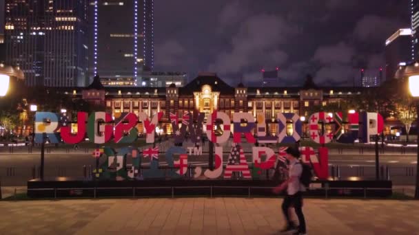 Vídeo de un enorme monumento tipográfico donde está inscrito RUGBY WORLD CUP 2019 JAPÓN en frente de la estación de Tokio por la noche . — Vídeo de stock