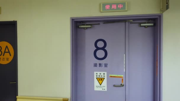 Право на левую панель видео пустой коридор японской больницы Токио в отделении радиологии IRM, чьи двери показывают слова "Меняющиеся комнаты", "комната МРТ-радиологии" — стоковое видео