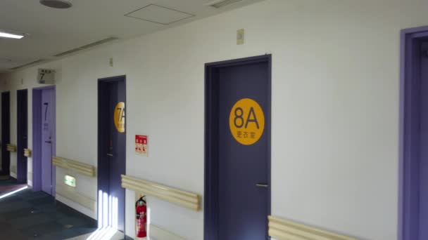 Слева направо видео пустого коридора японской больницы Токио в радиологическом отделении IRM, двери которого показывают слова "комната для смены", "комната для магнитно-резонансной томографии" — стоковое видео
