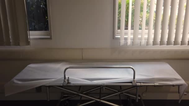 東京の日本の病院の廊下に白いシートを持つ空の金属ストレッチャーの傾斜ビデオまで. — ストック動画