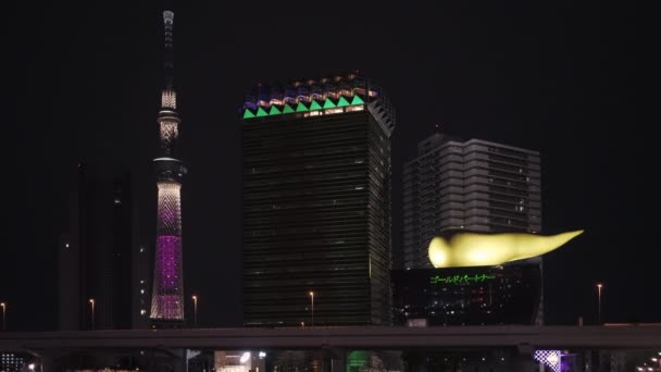 Vídeo estático noturno das Olimpíadas de Tóquio Jogos Paralímpicos 2020 mensagens de revezamento da tocha exibidas no marco turístico da chama dourada do Asahi Beer Hall e do Tokyo Skytree — Vídeo de Stock