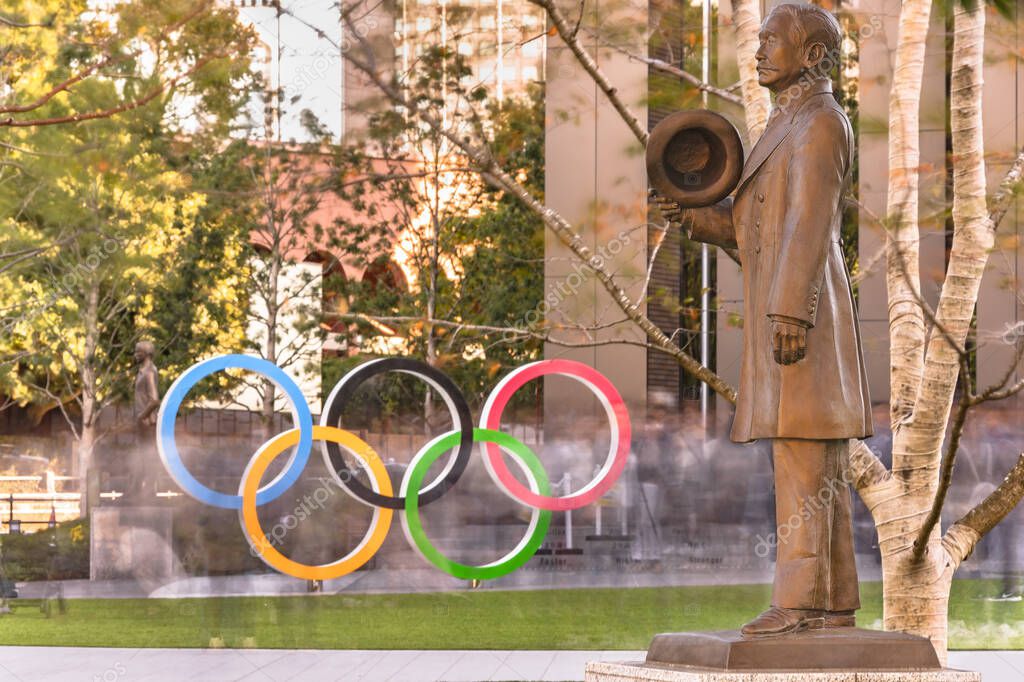 Tokyo, japan - november 17 2019: Bronze statue of the founder of Judo sport discipline Kano Jigoro who being the first Asian member of the International Olympic Committee in front of the Olympic Rings monument of the Japan Olympic Museum for the Toky