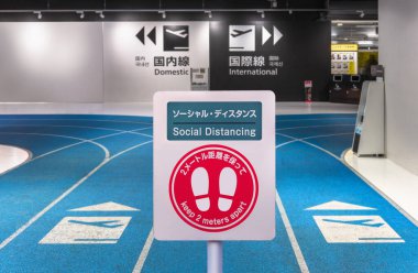Tokyo, Japonya 'daki Narita Uluslararası Havalimanı' nın 3 numaralı kalkış terminalinde yolcuları 2 metre ayrı tutmaya çağıran ayak izi simgesi ile sosyal uzaklık işareti.