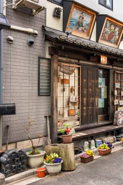 tokyo, japan - march 30 2020: Traditional Japanese wooden houses from the Showa era rehabilitated into retro Old-Fashioned restaurant in the quiet nostalgic and old town neighbourhood of Yanaka Ginza district and decorated with religious Ema plaques. clipart