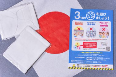 Tokyo, Japonya - 20 Mayıs 2020: Japon hükümeti tarafından kronik kıtlıkla başa çıkmak ve koronavirüsün (COVID-19) Japonya bayrağında yayılmasıyla mücadele etmek için gönderilen sosyal mesafeyi destekleyen bez maskeler ve broşür.