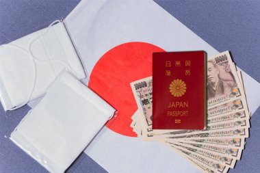 Tokyo, Japonya - 20 Mayıs 2020: Japon hükümet başkanı Abe Shinzo tarafından koronavirüsle (COVID-19) savaşmak için gönderilen kumaş maskeler ve 100.000 yen nakit para ve Japonya bayrağında pasaport taşıyan ekonomik işsizlik.