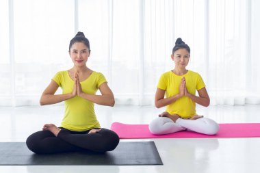İki Asyalı kadının güzelliği, iyi sağlık ve kasların esnekliği için yoga odasında iyi ve mutlu hissetmek amacıyla yoga yapıyor. Bu herkes için sağlıklı bir yaşam tarzı aktivitesi..