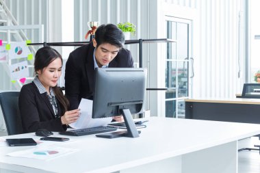 Bilgisayarlar ve beyin fırtınası yoluyla bilgi analiz eden genç iş adamları finansal veriler konusunda başarılı oldukları için mutlular. Modern ofisteki performansı analiz etmek için bir iş raporu getir.