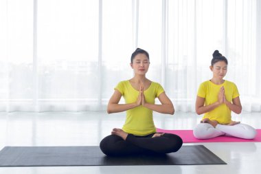 İki Asyalı kadının güzelliği, iyi sağlık ve kasların esnekliği için yoga odasında iyi ve mutlu hissetmek amacıyla yoga yapıyor. Bu herkes için sağlıklı bir yaşam tarzı aktivitesi..