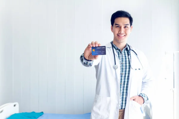 医師は彼の手にクレジットカードを示していますクレジットカードで医療費を支払うことについてのアイデアを示すために ストック画像