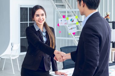 Genç Asyalı İşadamları, modern ofis içinde ticaret önerileri üzerinde anlaşmak için finansal bir iş konsepti üzerinde duruyor ve tokalaşıyorlar..