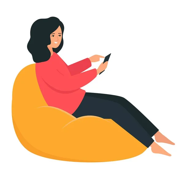 La chica feliz está sentada en una silla de frijoles. Muebles sin marco. Una mujer sostiene un teléfono inteligente en su mano . — Vector de stock